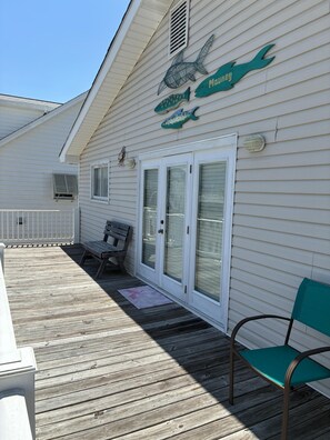 A house with a covered deck, a bench, a chair, and a fish mural on the wall. - 3 Bedroom home with access to the canal! (Supply)