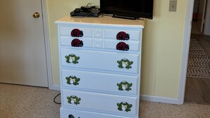 A white dresser with frog designs, a flat-screen TV on the wall, and a door to the left. - 3 Bedroom home with access to the canal! (Supply)