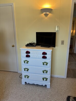 A white dresser with frog designs, a flat-screen TV on the wall, and a door to the left. - 3 Bedroom home with access to the canal! (Supply)