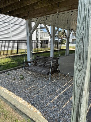 A wooden swing bench under a covered area with a metal fence in the background. - 3 Bedroom home with access to the canal! (Supply)