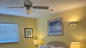 A bedroom with a bed, two bedside tables, a ceiling fan, and wall-mounted lamps. - 3 Bedroom home with access to the canal! (Supply)