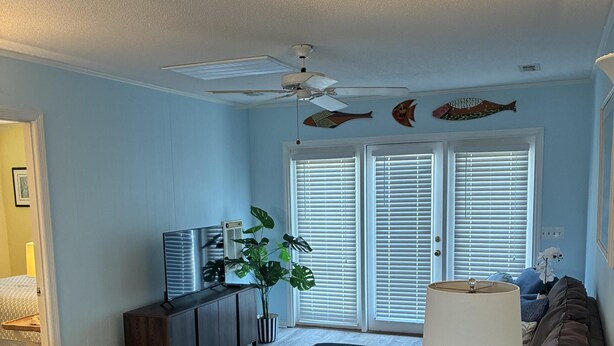 A living room with a ceiling fan, a TV, a plant, and a sofa. - 3 Bedroom home with access to the canal! (Supply)