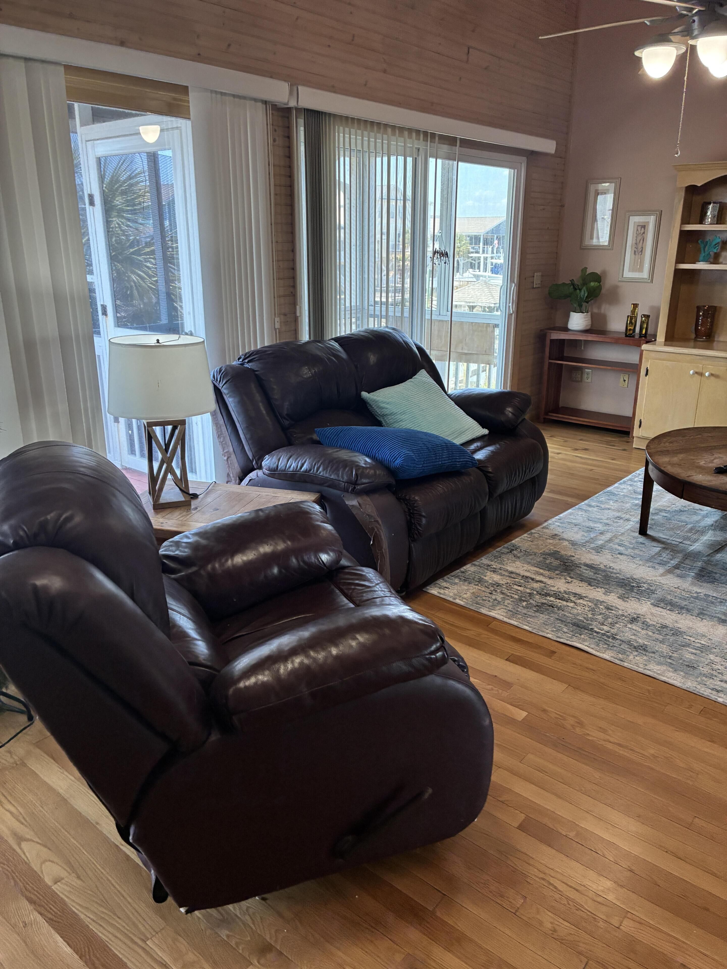 A living room with a leather sofa, a wooden coffee table, and a view through large windows.