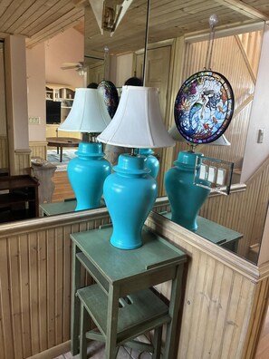 A room with a wooden ceiling, a mirrored wall, and a blue table lamp. - Welcome to Holden It Down!!!, your perfect coastal escape on the serene canals of Holden Beach. (Supply)