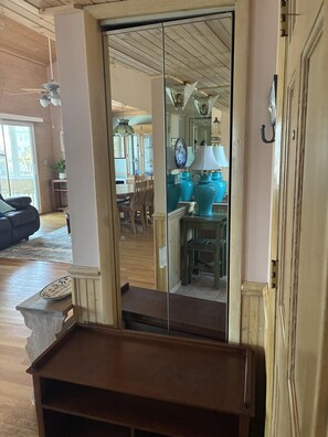 A room with a wooden ceiling, a sliding glass door leading to a dining area, and a small wooden table with a decorative plate. - Welcome to Holden It Down!!!, your perfect coastal escape on the serene canals of Holden Beach. (Supply)