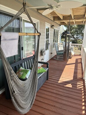 A wooden deck with a hammock, a bench with cushions, and a ceiling fan. - Welcome to Holden It Down!!!, your perfect coastal escape on the serene canals of Holden Beach. (Supply)