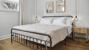 Ein Schlafzimmer mit einem Bett, Nachttischen und einem Fenster mit Vorhängen.