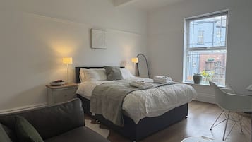 A bedroom with a bed, bedside tables, a desk, and a window.