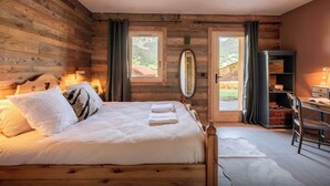 A wooden-paneled bedroom with a bed, a desk, and a view of the outdoors. - Chalet Source Eve - The ideal base in the Espace Diamant - OVO Network (Praz-sur-Arly)
