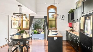 A modern kitchen with a central island, black cabinetry, and a large refrigerator. - Church Conversion @ 39 Hoddle Street (Robertson)