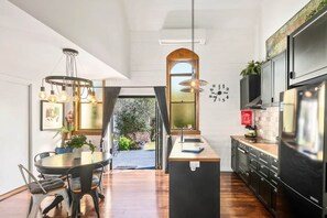 A modern kitchen with a central island, black cabinetry, and a large refrigerator. - Church Conversion @ 39 Hoddle Street (Robertson)