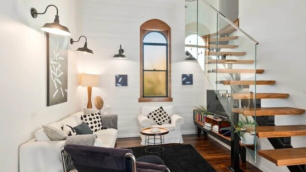 A modern living room with a glass staircase, white walls, and minimalist furniture. - Church Conversion @ 39 Hoddle Street (Robertson)
