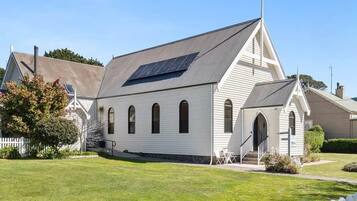 A white building with a sloped roof, a solar panel, and a small porch with steps.
