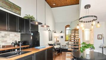 A modern kitchen with a wooden island, black cabinets, and pendant lighting.
