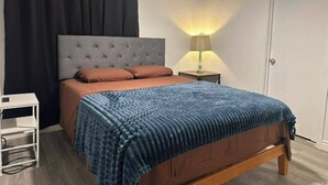 Una camera da letto con un letto, un comodino, una lampada e un condizionatore d'aria.