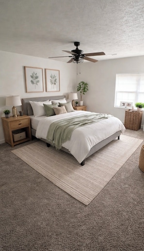 A bedroom with a bed, nightstands, a ceiling fan, a window with blinds, and a plant.