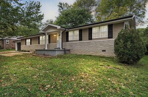 A two-story house with a stone facade, a front porch, and a well-maintained lawn. - The Ozark Gathering Place Spacious Family Retreat Near Springfield & Branson (Ozark)