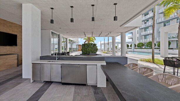 Una cocina moderna con refrigerador integrado, televisor de pantalla plana y zona de estar con sillas de mimbre.