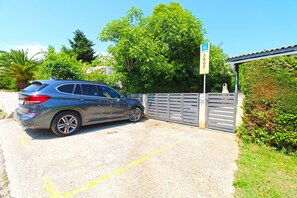 A gray car parked in a driveway with a gated entrance, surrounded by greenery and a clear blue sky. - Apartment 2435/208211 (Istria - Premantura), 450m from the beach (Premantura)
