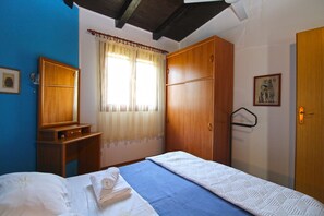 A bedroom with a bed, a wooden wardrobe, a small bedside table, a window with curtains, and a door. - Apartment 2435/208211 (Istria - Premantura), 450m from the beach (Premantura)