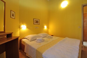 Ein Hotelzimmer mit zwei Betten, einem Holzschrank und Wandleuchten.
