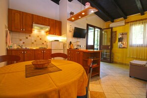 A kitchen with wooden cabinets, a dining table with a yellow tablecloth, and a television mounted on the wall. - Apartment 2435/208212 (Istria - Premantura), 450m from the beach (Premantura)