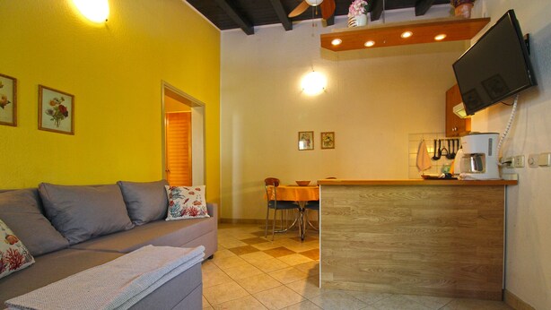 Un espacio habitable compacto con sofá, mesa de comedor y kitchenette.