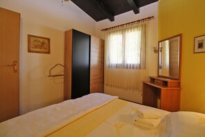 A bedroom with a bed, a wooden wardrobe, a mirror, and a window with curtains. - Apartment 2435/208212 (Istria - Premantura), 450m from the beach (Premantura)