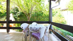 Un patio al aire libre con mesa y sillas, rodeado de follaje.