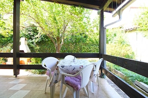 An outdoor patio with a table and chairs, surrounded by greenery. - Apartment 2435/208212 (Istria - Premantura), 450m from the beach (Premantura)