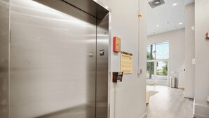 A modern elevator with a metallic finish, a fire alarm, and an evacuation plan sign. - King Bed + Balcony Walk to Ponce City Market & BeltLine in Atlanta (Atlanta)