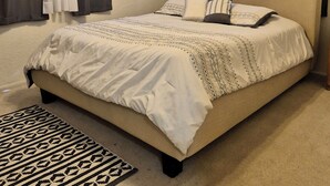 Ein Schlafzimmer mit einem Bett, einem Deckenventilator und einem gemusterten Teppich.