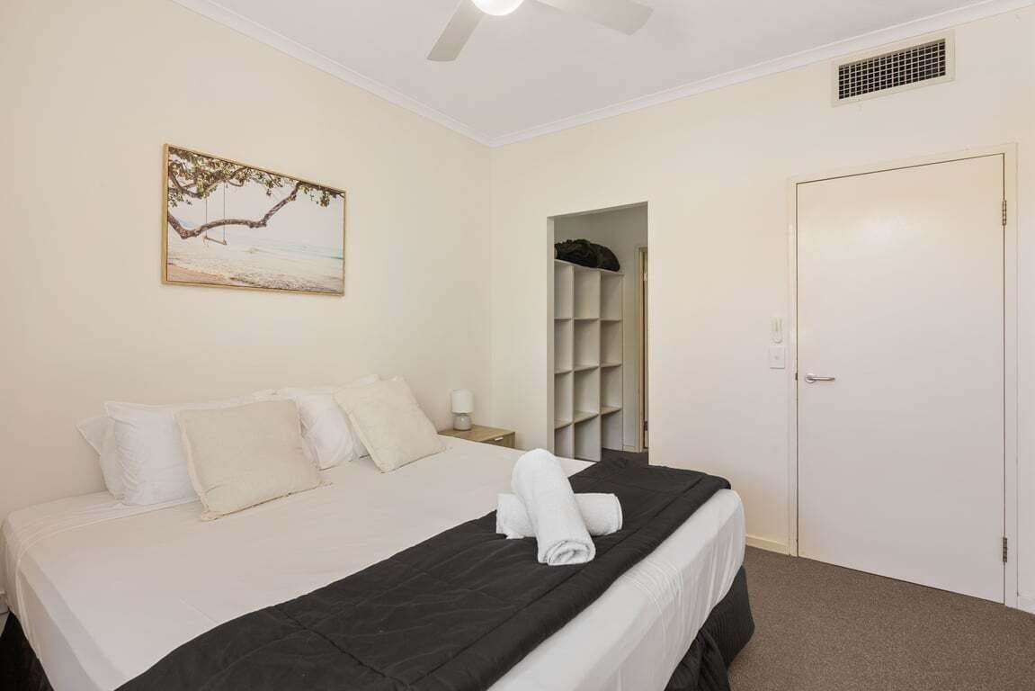 Une chambre d’hôtel avec un lit, un tableau, une armoire et une porte.