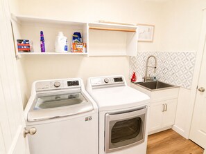 A compact laundry area with a washing machine, dryer, and a sink with a geometric backsplash.