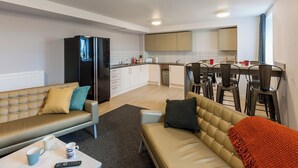Ein modernes Wohnzimmer mit Sofa, Couchtisch und einem Essbereich mit Stühlen und Tisch.