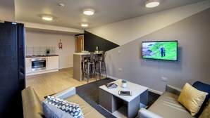 Ein modernes Wohnzimmer mit einer Couch, einem Couchtisch und einem Fernseher, der eine Naturansicht zeigt.