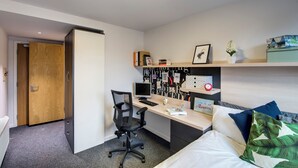 Ein modernes Schlafzimmer mit Schreibtisch, Stuhl, Bett und einer Wand mit Dekoration.