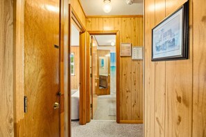 A hallway with wooden doors leading to a bathroom and a bedroom. - Surfside Rendezvous - Semi-oceanfront  with ocean views, easy beach access, and deck (Nags Head)