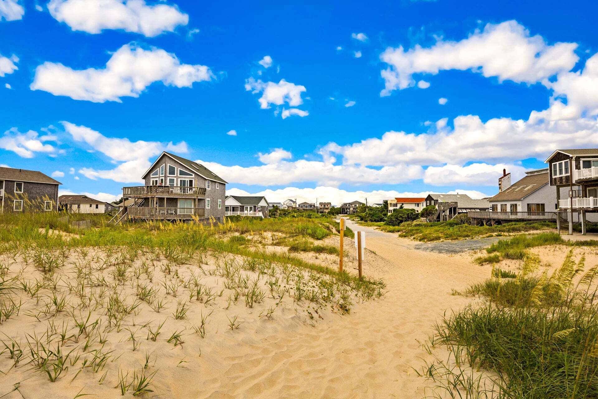 A coastal pathway leading to houses with a clear sky.