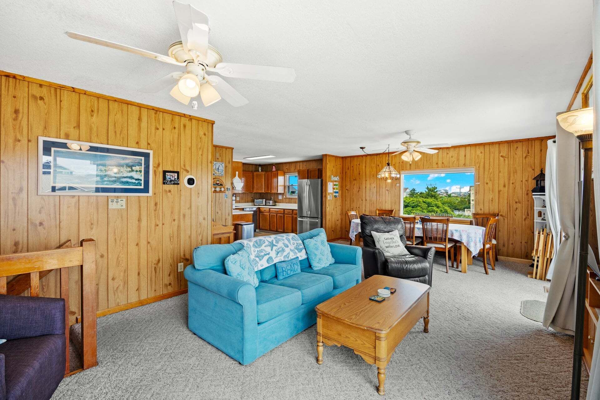 A cozy cabin interior with a blue sofa, wooden coffee table, and a dining area with a view.