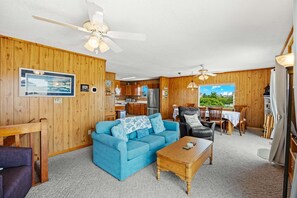 Ein gemütliches Blockhaus-Interieur mit einem blauen Sofa, einem Holztisch und einem Essbereich mit Blick.