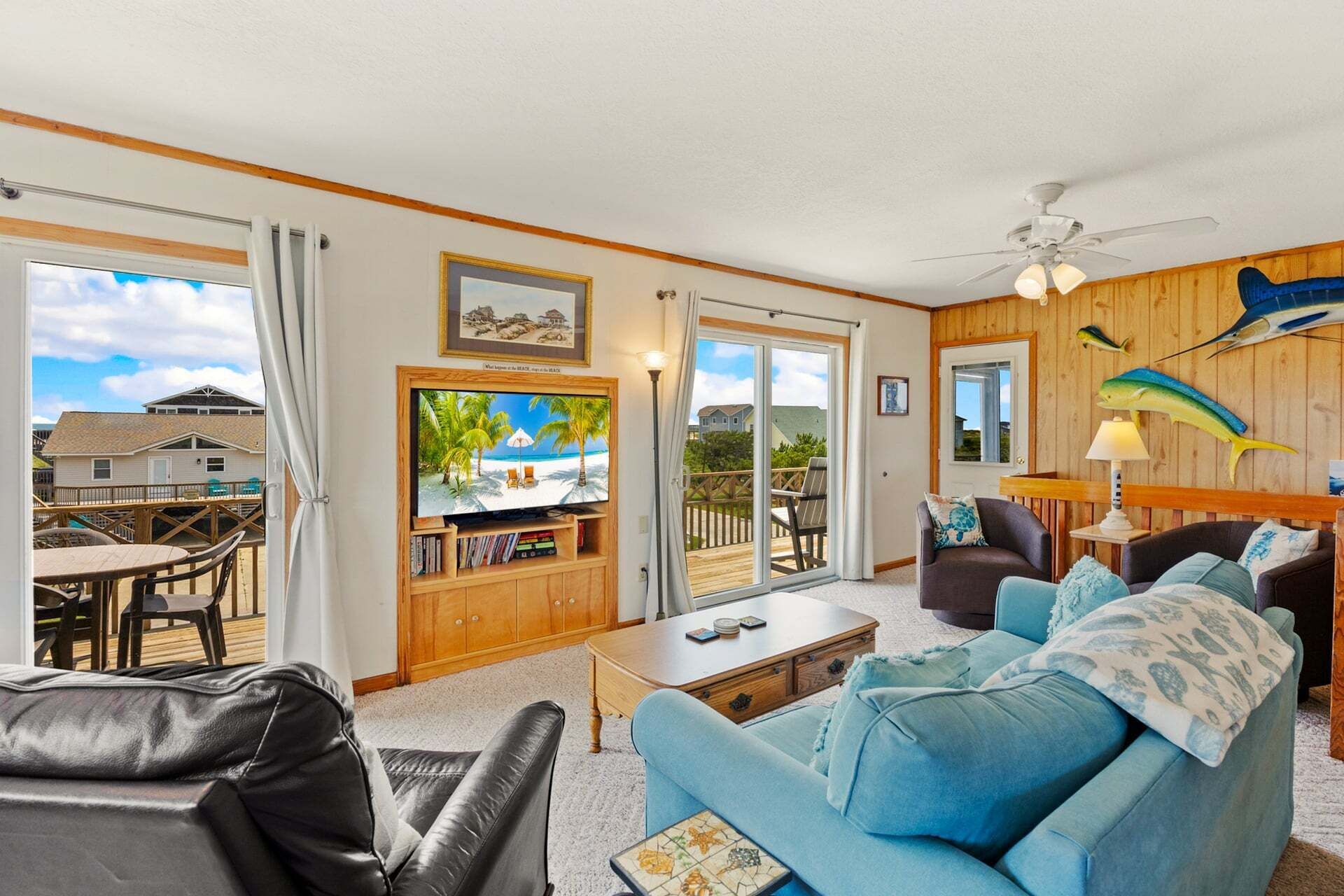 A living room with a large TV, a blue sofa, a leather chair, and a wooden coffee table.