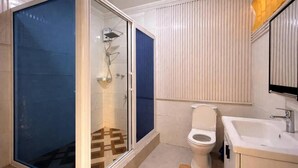 Un baño con ducha de vidrio, inodoro y lavamanos.