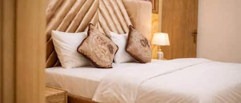 A bed with a headboard, pillows, a bedside table, and a lamp.