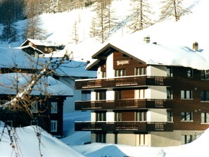 A multi-story hotel with a prominent 'Bergrose' sign, surrounded by snow-covered trees and buildings. - Bergrose Appartement/Fewo 5-Bettwohnung Nr. 2 by Interhome (Saas-Fee)