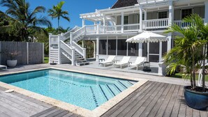 Een tweelaags huis met een zwembad, buitenmeubels en een overdekt terras.