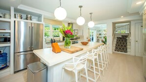 Een moderne keuken met een centraal eiland, roestvrijstalen apparatuur en hanglampen.