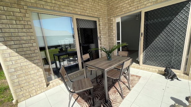 A patio with a table and chairs, a zebra-patterned rug, and a dog. - Bunker Down in Beautiful Bargara pet friendly on the Fraser Coast of Queensland (Bargara)