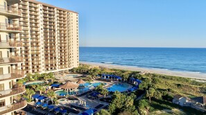 A high-rise hotel with multiple balconies, a beachfront pool area, and a clear view of the ocean. - Luxury 4-bedroom house in North Beach Resort, North Myrtle Beach, SC (North Myrtle Beach)