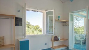 A room with a window, a desk, a chair, and a small shelf with towels. - Casa Valverde, Alghero (Alghero)